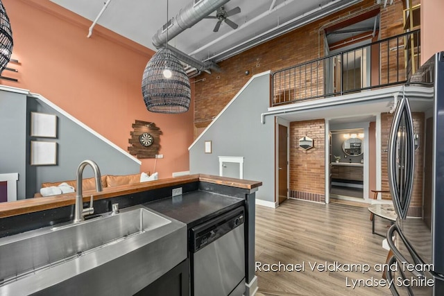 kitchen with stainless steel dishwasher, a sink, baseboards, freestanding refrigerator, and wood finished floors