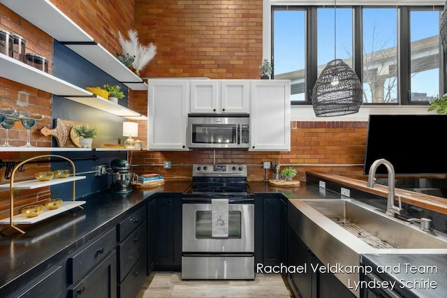kitchen with tasteful backsplash, open shelves, a sink, white cabinetry, and appliances with stainless steel finishes