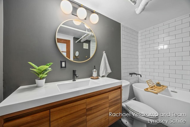 full bath featuring a freestanding tub, toilet, and vanity