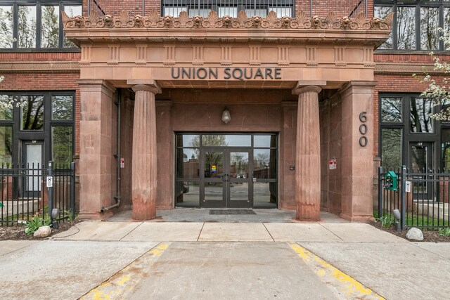 view of exterior entry with fence, uncovered parking, and french doors