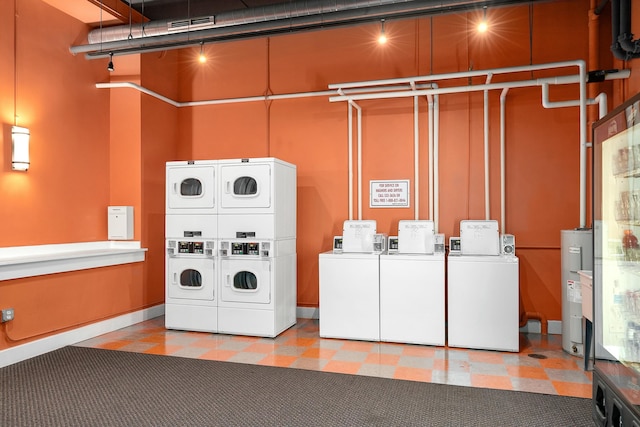 community laundry room featuring light floors, washer and dryer, water heater, and stacked washing maching and dryer