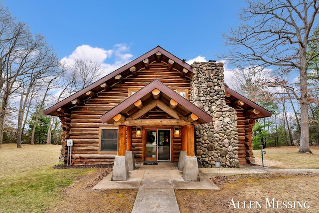 log-style house featuring a chimney, a front lawn, and log exterior