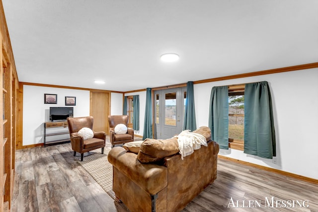 living area with crown molding, wood finished floors, and a healthy amount of sunlight
