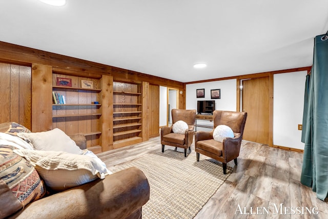 living area featuring light wood-style flooring, built in features, and stairway