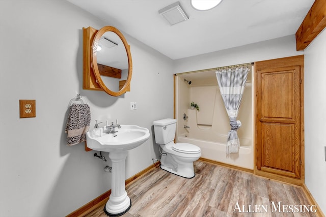 full bathroom with baseboards, shower / bath combination with curtain, a sink, toilet, and wood finished floors