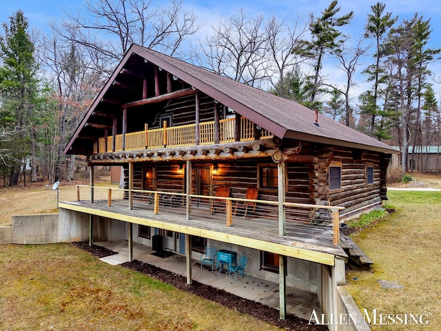 rear view of property featuring a patio area, log exterior, a deck, and a yard