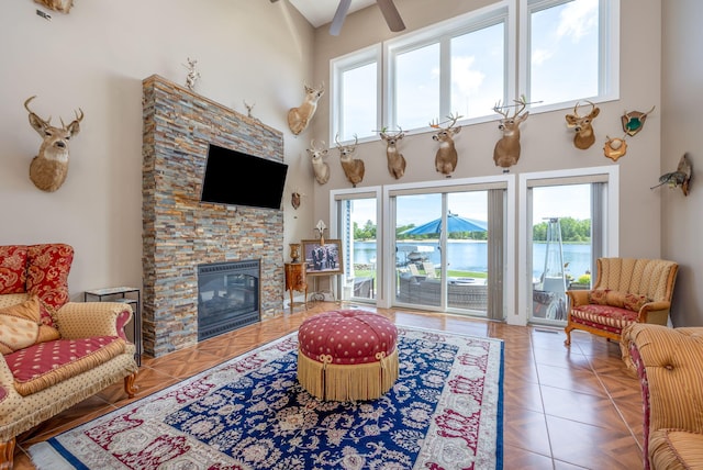 7140 Holiday Dr, Canadian Lakes, MI 49346 - living room featuring a high ceiling, a stone fireplace, and ceiling fan