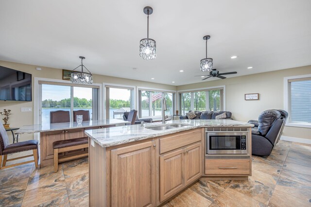 7140 Holiday Dr, Canadian Lakes, MI 49346 - kitchen with light stone countertops, a kitchen island with sink, stainless steel microwave, a sink, and open floor plan