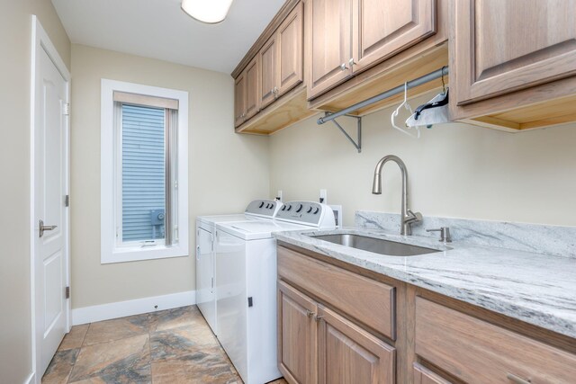 7140 Holiday Dr, Canadian Lakes, MI 49346 - clothes washing area featuring baseboards, stone finish floor, cabinet space, washer and dryer, and a sink
