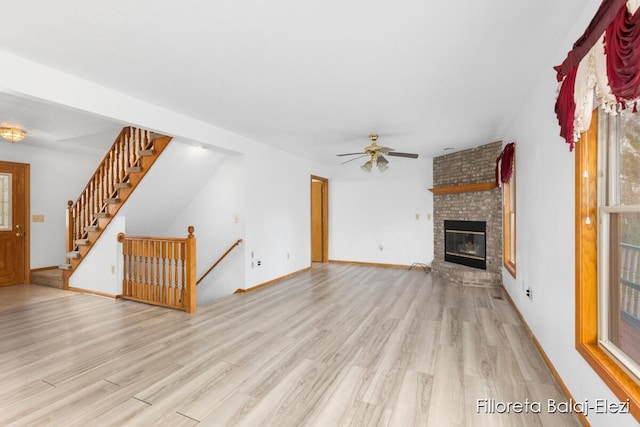 unfurnished living room featuring a brick fireplace, a ceiling fan, wood finished floors, and baseboards