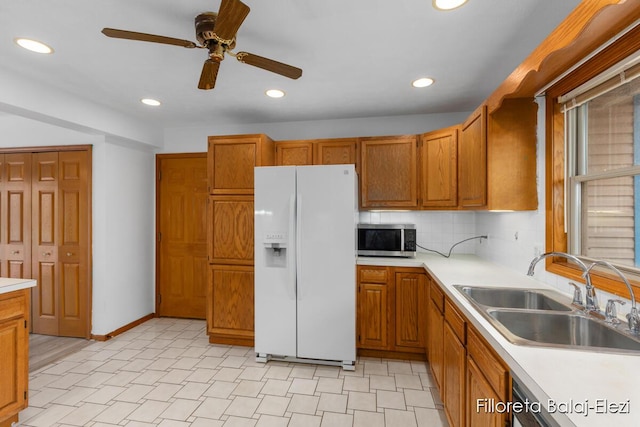 kitchen featuring a sink, light countertops, ceiling fan, stainless steel microwave, and white refrigerator with ice dispenser
