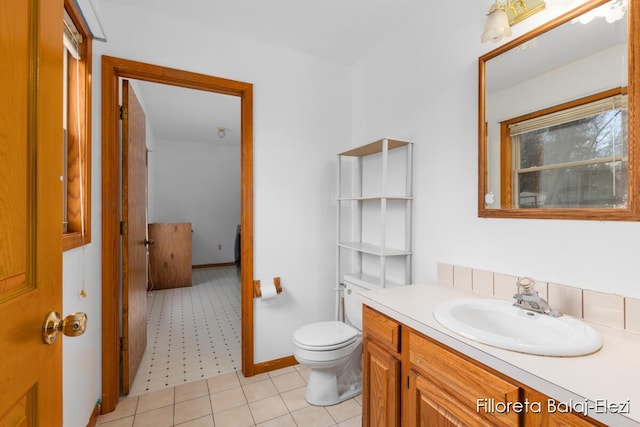 bathroom with toilet, vanity, and baseboards