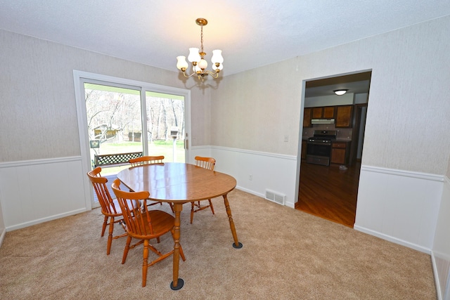 dining room featuring a notable chandelier, carpet, visible vents, and a wainscoted wall