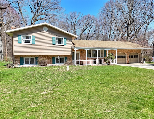 tri-level home featuring a garage, brick siding, a front lawn, and covered porch