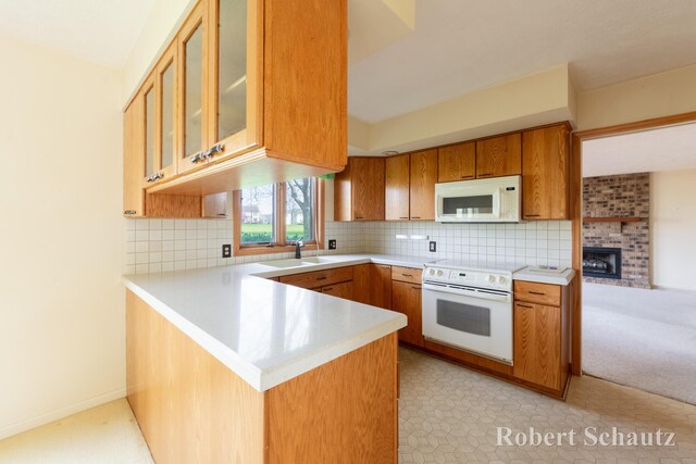 kitchen with light countertops, a sink, a peninsula, glass insert cabinets, and white appliances