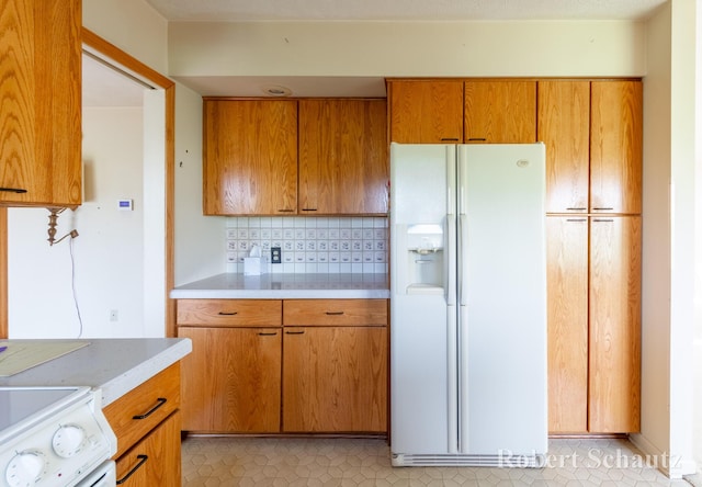 kitchen featuring brown cabinetry, decorative backsplash, white refrigerator with ice dispenser, light countertops, and range