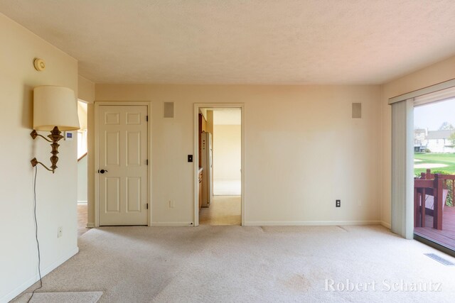 empty room featuring baseboards, light carpet, and visible vents