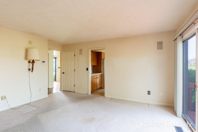 unfurnished room featuring baseboards, visible vents, and light carpet