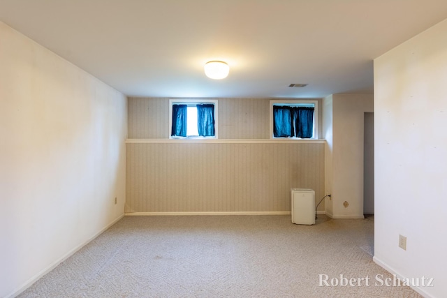 below grade area featuring baseboards, visible vents, carpet, and a wainscoted wall