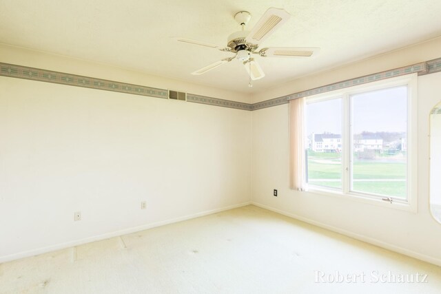 carpeted spare room with baseboards, visible vents, and ceiling fan