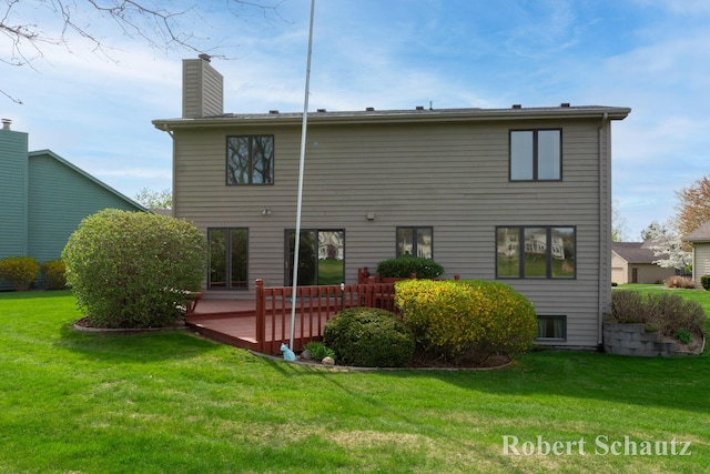 back of property with a lawn, a wooden deck, and a chimney
