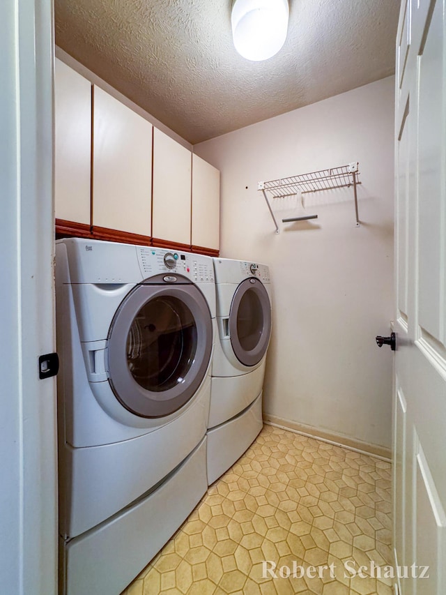 laundry room featuring a textured ceiling, cabinet space, and washer and dryer
