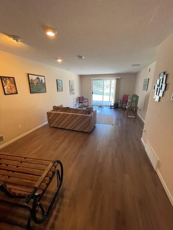 living area with wood finished floors, baseboards, and visible vents