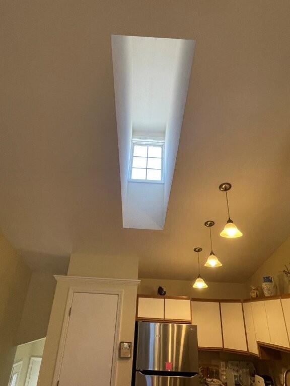 details with decorative light fixtures, freestanding refrigerator, and white cabinets