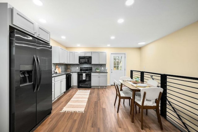 308 Hillview St, Buchanan, MI 49107 - kitchen with recessed lighting, dark countertops, decorative backsplash, black appliances, and wood finished floors
