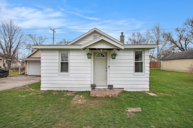 view of front of house with an outdoor structure, a chimney, aphalt driveway, a front yard, and a garage