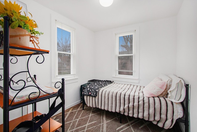 bedroom with dark carpet, baseboards, and multiple windows