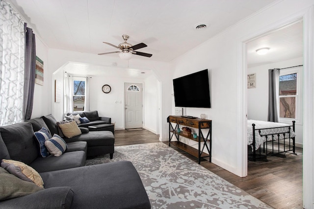 living area featuring visible vents, baseboards, a ceiling fan, and wood finished floors