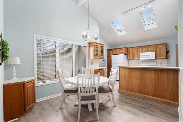 8170 Talaria Ter, Kalamazoo, MI 49009 - dining room featuring rail lighting, high vaulted ceiling, light wood-style floors, a chandelier, and a skylight