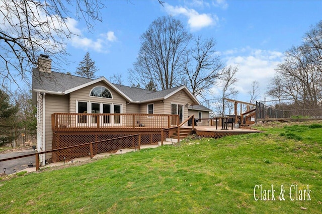 rear view of property with a yard, roof with shingles, a chimney, and a deck