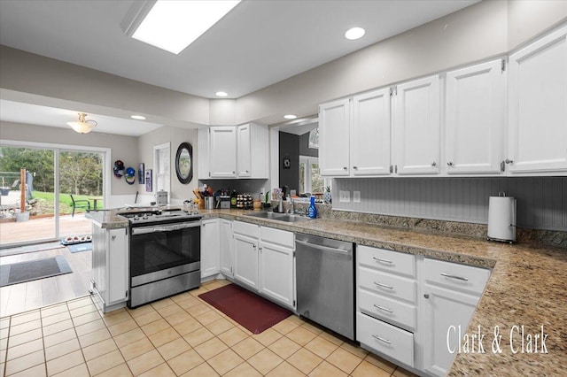 kitchen featuring white cabinets, recessed lighting, a sink, a peninsula, and appliances with stainless steel finishes