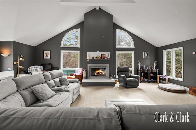carpeted living room with plenty of natural light, a glass covered fireplace, and high vaulted ceiling