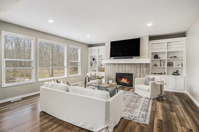 living area with baseboards, recessed lighting, a tiled fireplace, dark wood-style floors, and visible vents