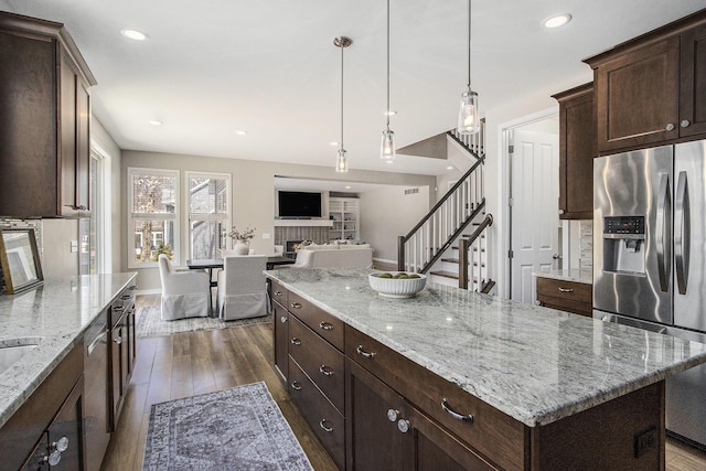 kitchen with a center island, a brick fireplace, dark wood-style flooring, open floor plan, and appliances with stainless steel finishes