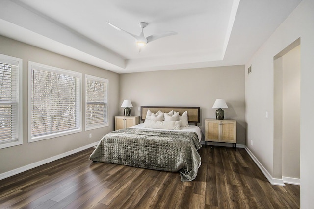 bedroom featuring visible vents, a tray ceiling, and wood finished floors