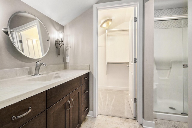 bathroom with a spacious closet, vanity, baseboards, and a stall shower