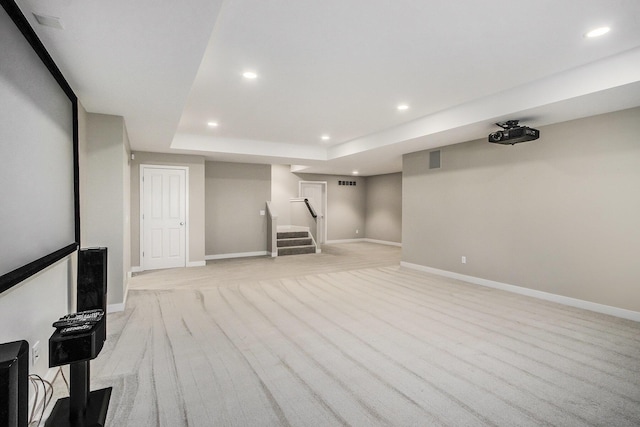 finished below grade area with light carpet, stairs, baseboards, and recessed lighting