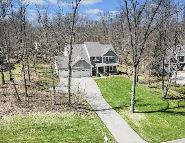 view of front of home featuring a front lawn, an attached garage, covered porch, and driveway