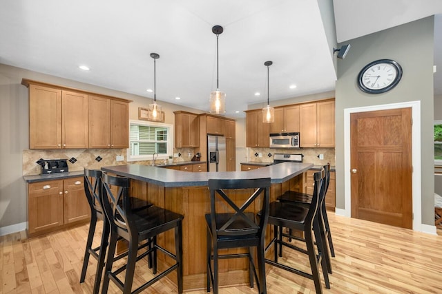 8702 E 98th St, Howard City, MI 49329 - kitchen with appliances with stainless steel finishes, dark countertops, light wood finished floors, backsplash, and a kitchen island