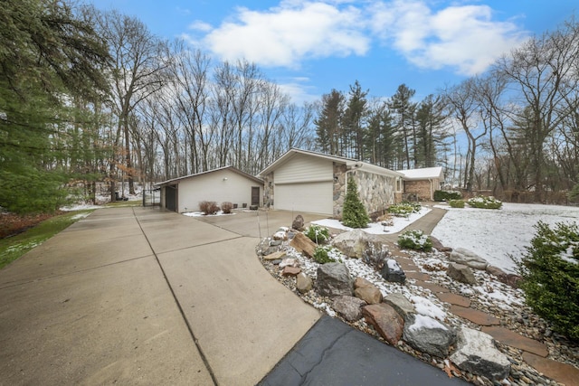 view of property exterior with a garage, driveway, stone siding, and an outdoor structure
