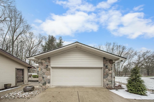 view of side of home with concrete driveway, an outdoor structure, stone siding, and a garage