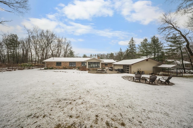 snow covered house with fence, a fire pit, and a chimney