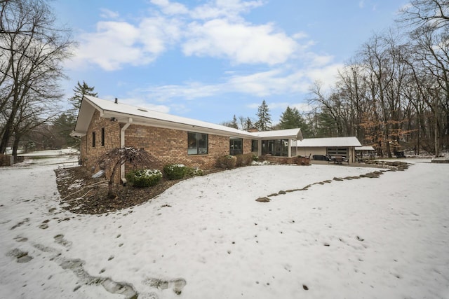 snow covered back of property featuring brick siding
