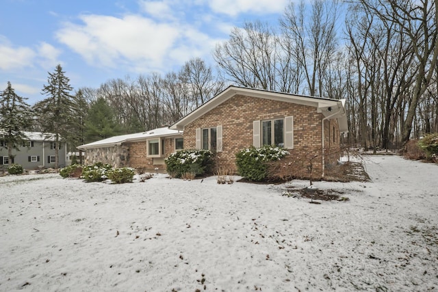 view of snowy exterior featuring brick siding