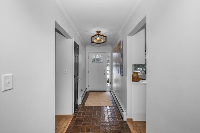 hallway with brick floor, baseboard heating, baseboards, and a notable chandelier