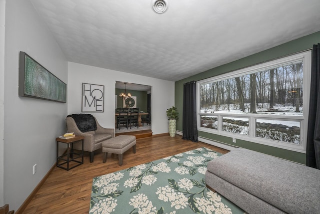 living area featuring a baseboard radiator, wood finished floors, baseboards, and an inviting chandelier